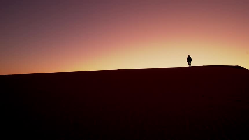 Someone is walking through the desert at dusk