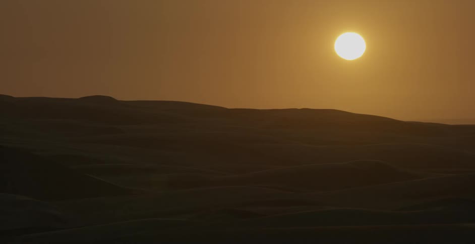 The sun shines over sand dunes in a desert