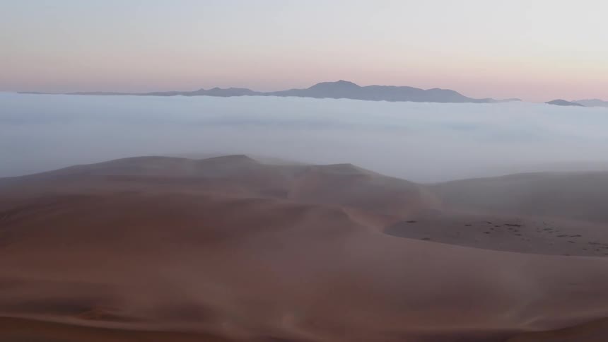 The sand leads to the water and fog ahead