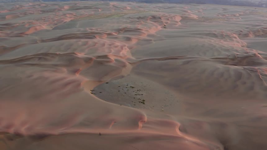 Many snow drifts sit with mountains in the distance