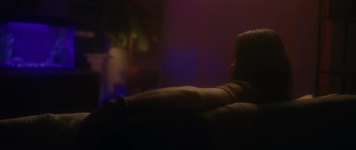 A man sits back on a couch looking at an aquarium