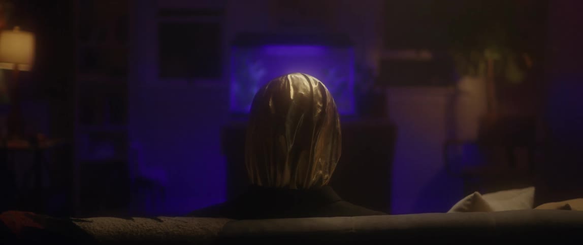 A person with a bag over their head is sitting on the couch