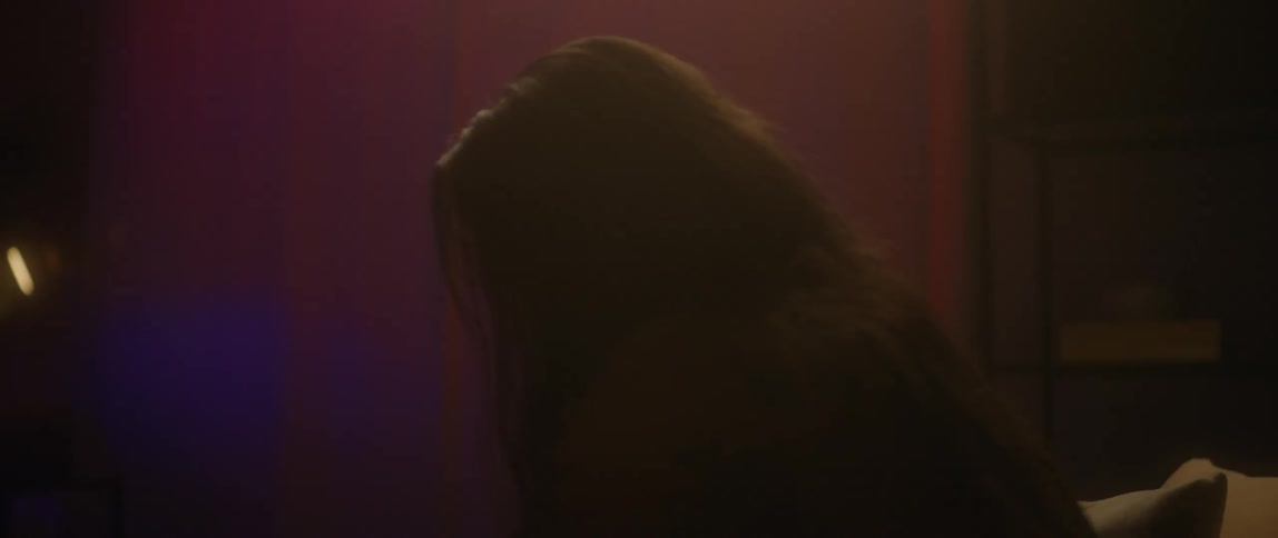 A man is sitting on a couch looking down at the floor