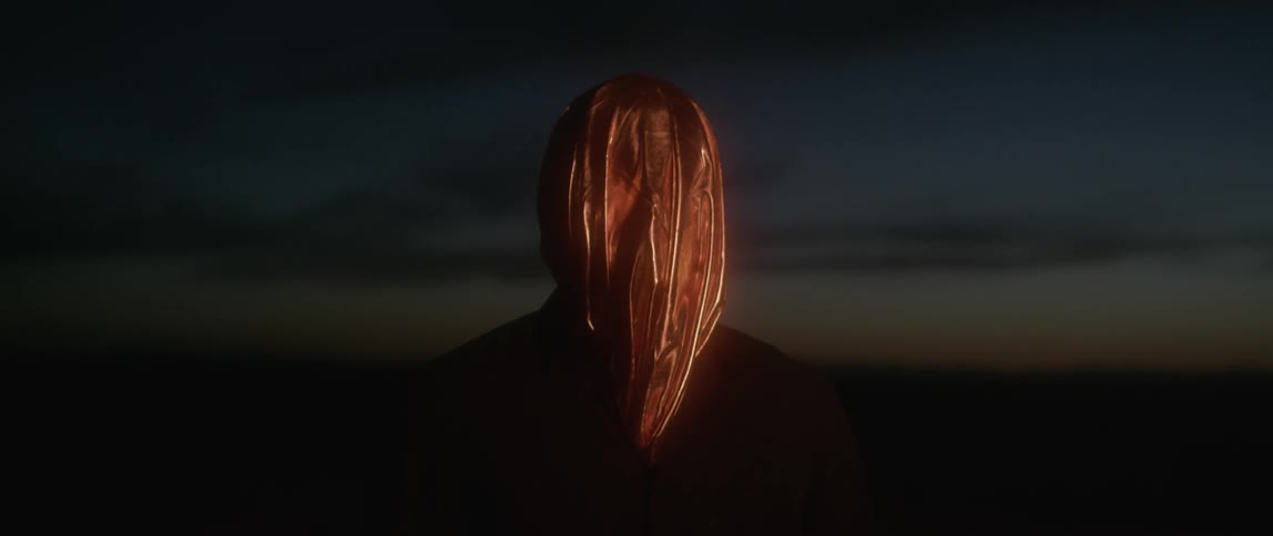 Person wearing a bag over their head standing outside at night