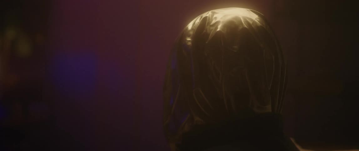 A masked figure stands in a dim room