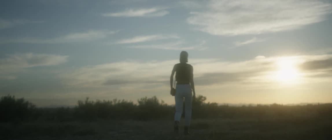 Woman wearing white pants walks under a blue sky