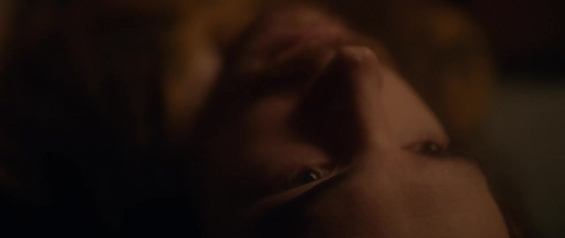 A man with long hair is leaning back on the couch looking at the ceiling