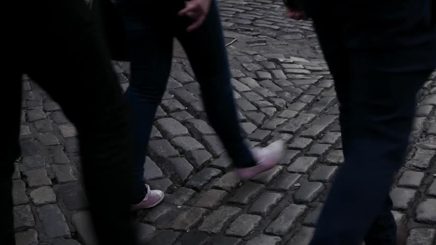 People walk over a cobblestone street