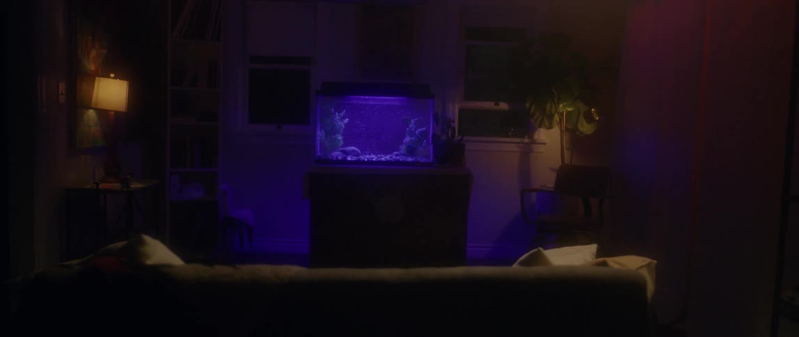 A purple fish tank is glowing in someone's living room