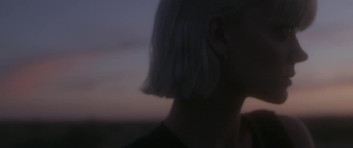 A woman stands outside at sunset