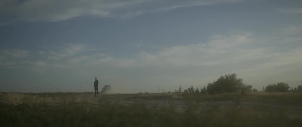 A person stands on the field as a car passes