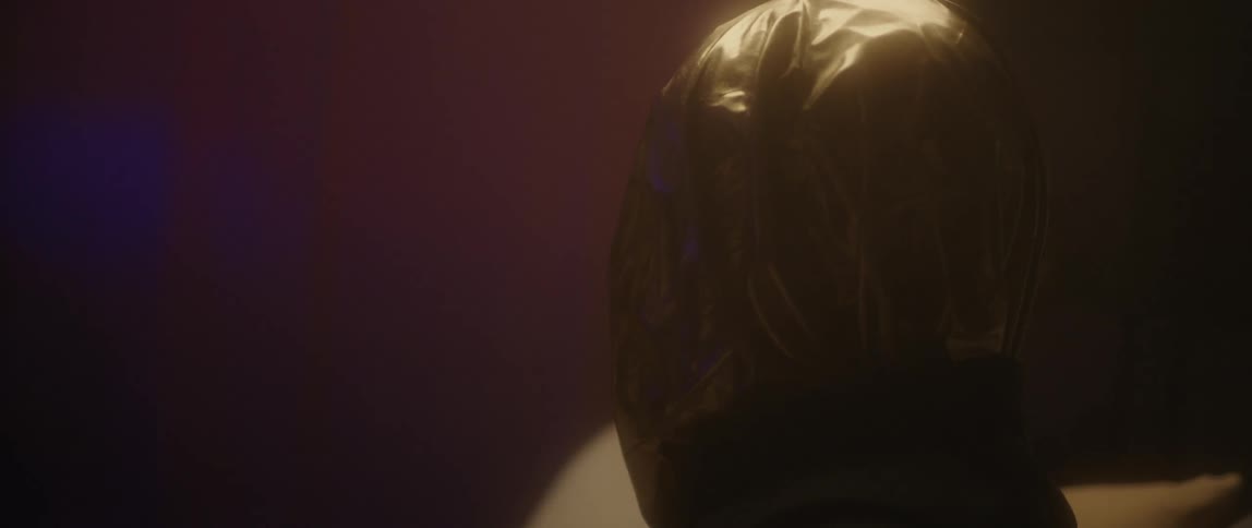 A woman with a bag over her head is sitting on the couch in a foggy room
