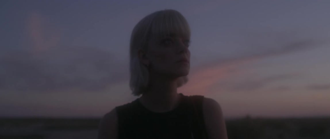A woman is looking at something off screen at dusk