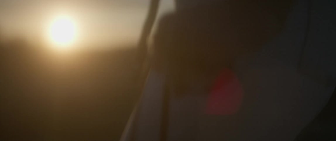 A woman walks with a purse outside at sunset