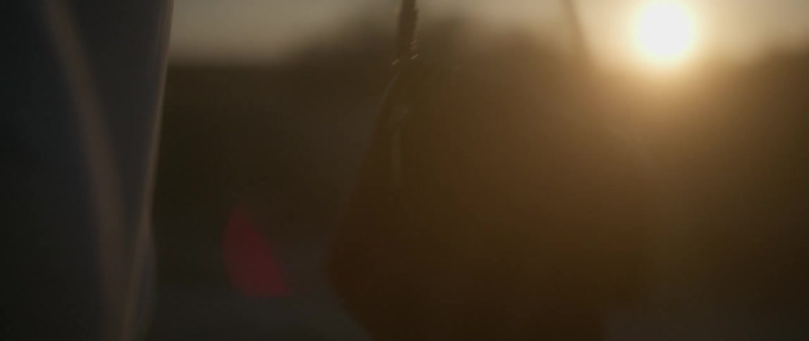 Person holding a coiled rope outside at sunset