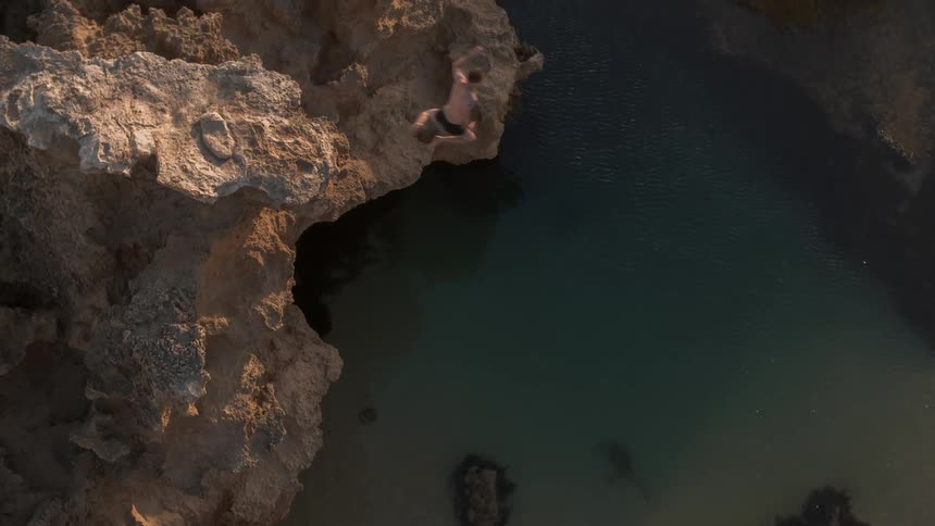 Man jumps off a cliff into the water below