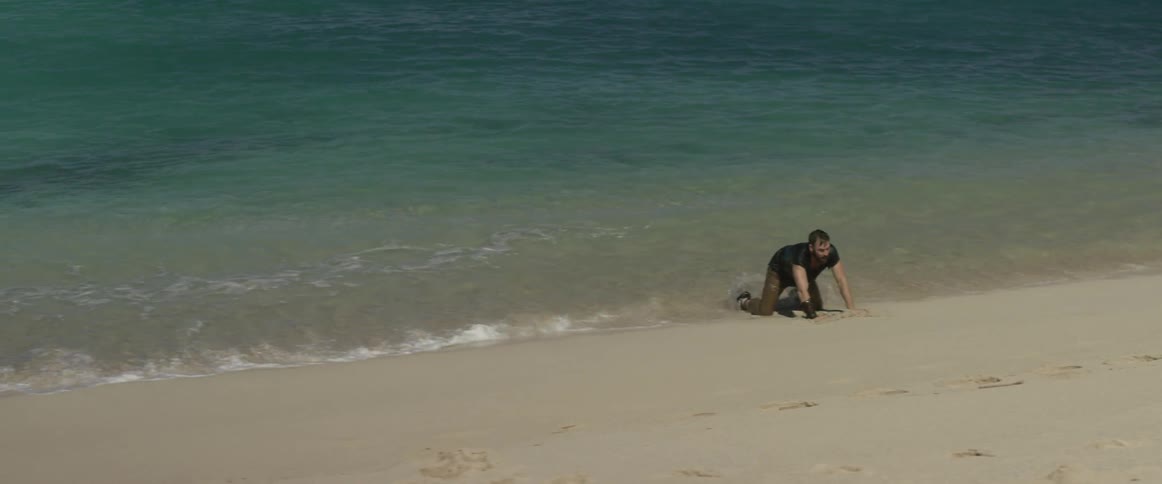 Ocean waves flowing around man washed up on sunny beach