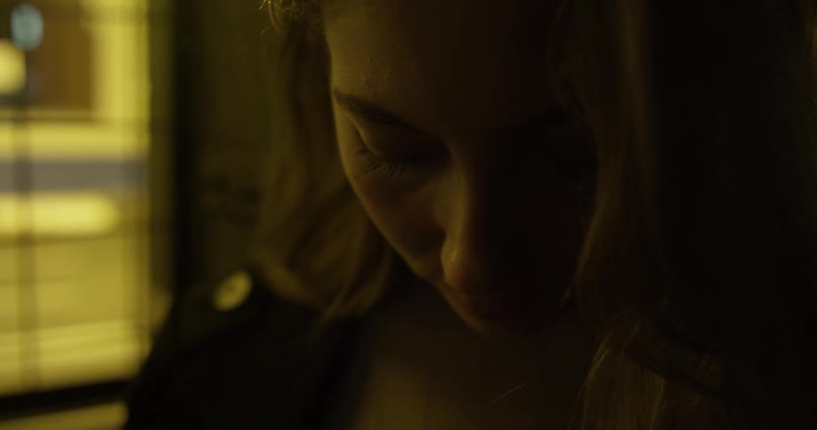 A woman looks down in a dark room