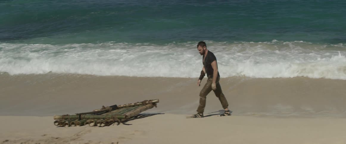 Man walking through waves on sunny beach over to wooden raft