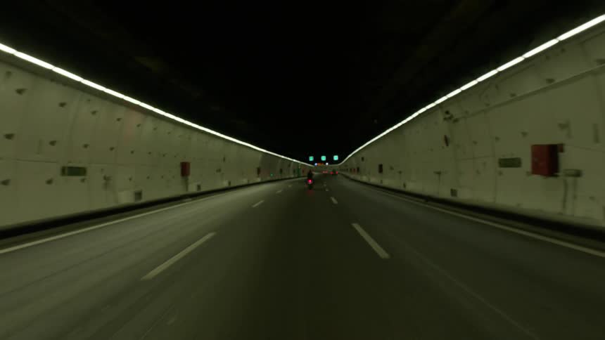 A motorcycle travels in a three lane tunnel