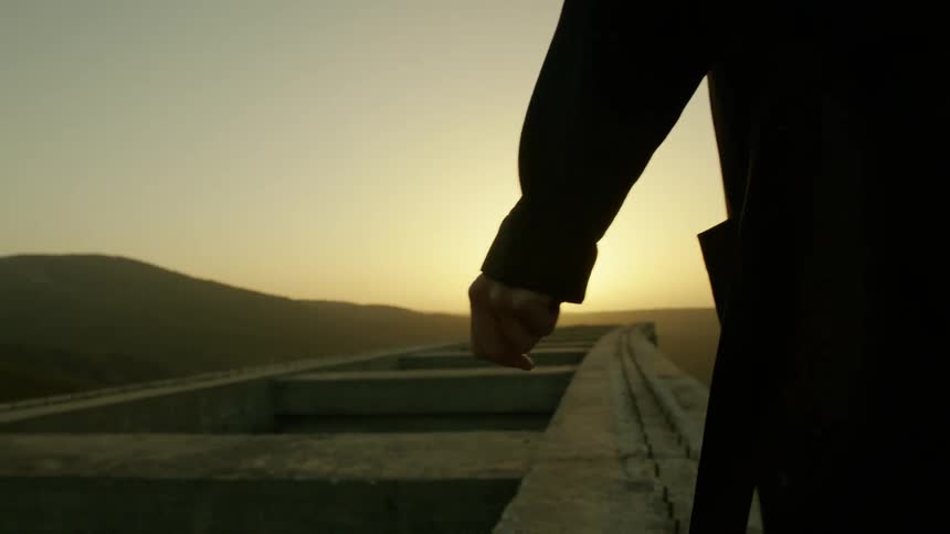 A person walks along the stone wall at dawn