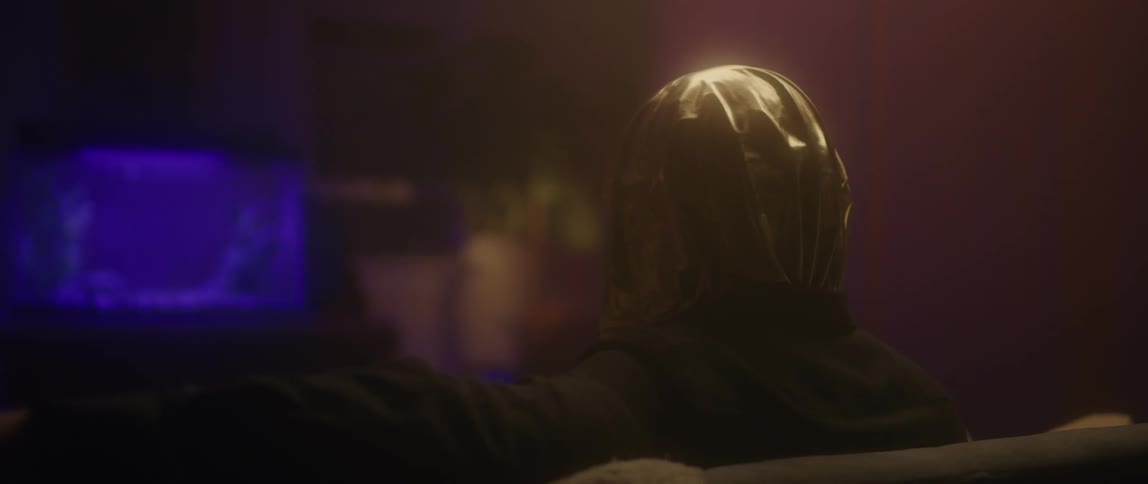 A person sits on a couch with a bag over his head