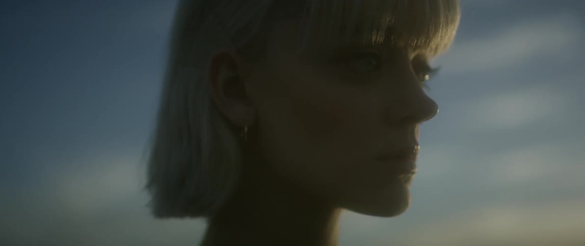 A woman looks around at sunset