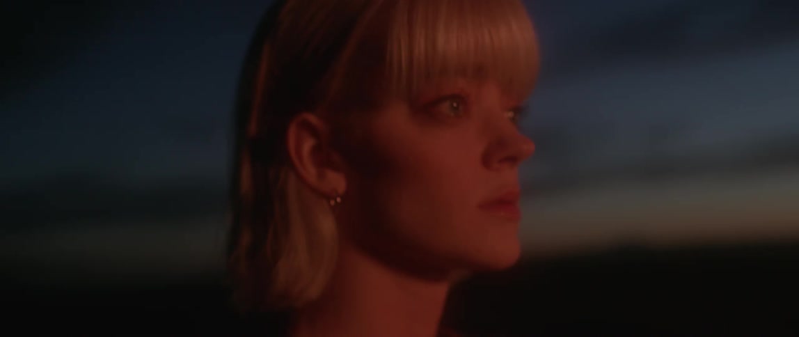 A woman blinks and walks forward at dawn