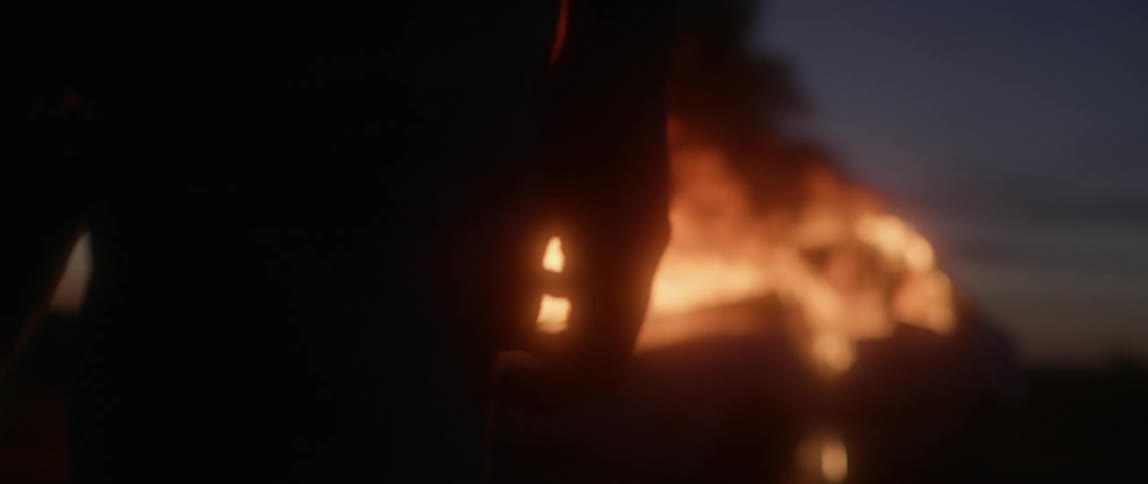 A car is burning as someone watches