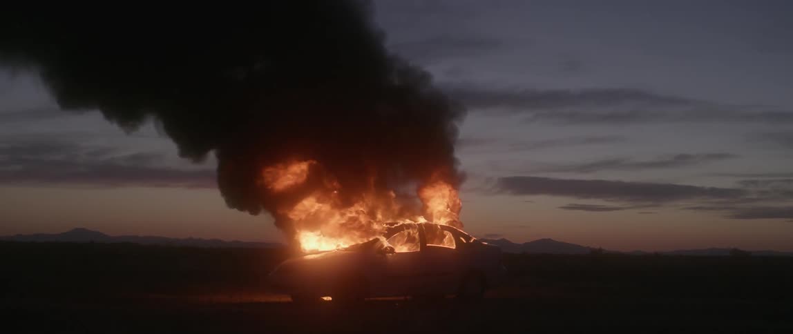 Flames and black smoke rise from a burning car