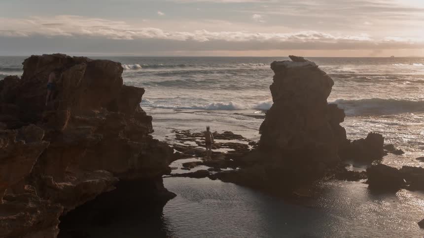 A man jumps from the top of a cliff and lands feet first in the water