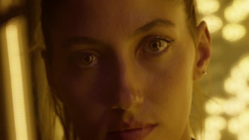 A woman looks straight ahead while standing indoors