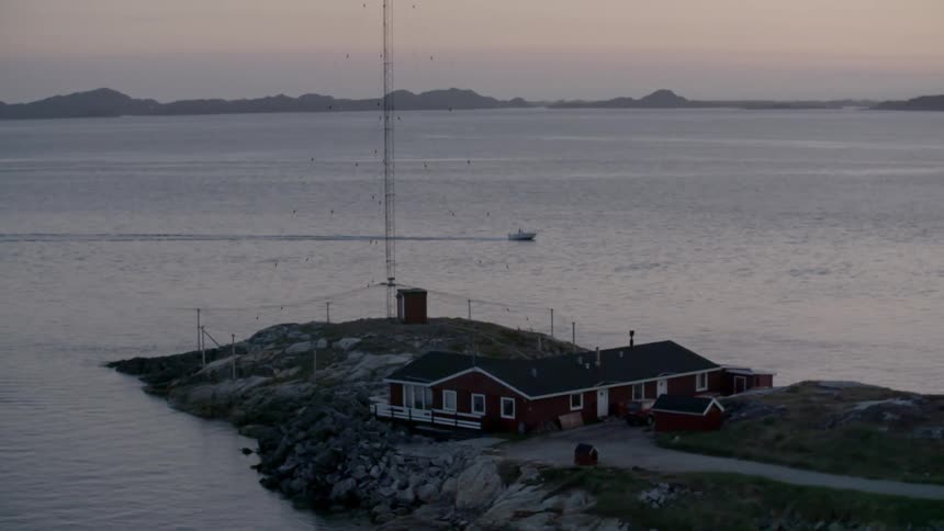 Aerial view of a house near the water as a boat passes
