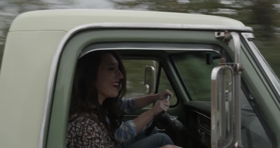 Two teenagers are riding in an old pickup truck