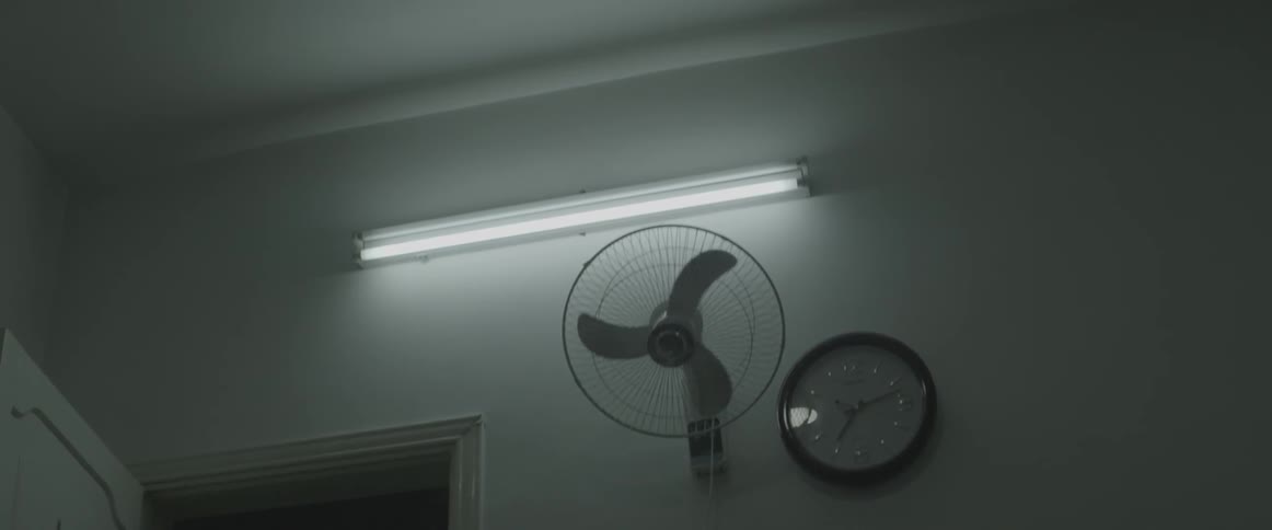 A fan's blades twirl to a stop inside a building at night