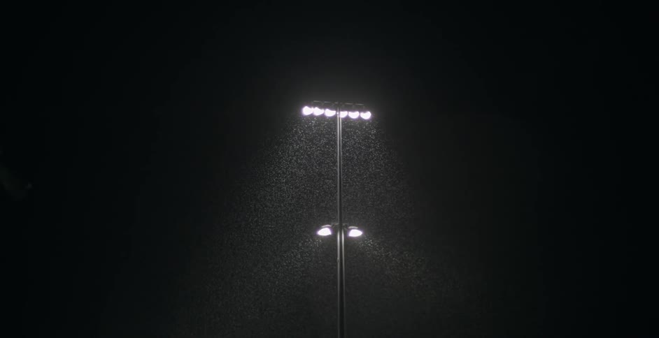 Stadium-type lights illuminate falling rain at night