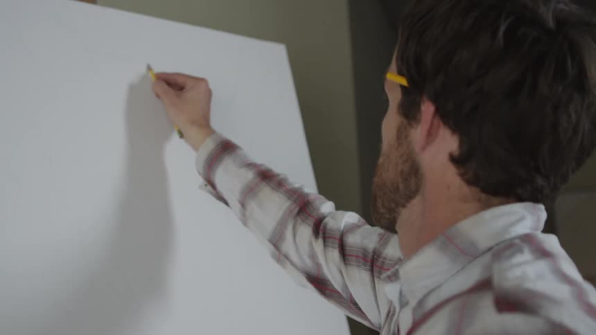 A white man drawing on a blank canvas