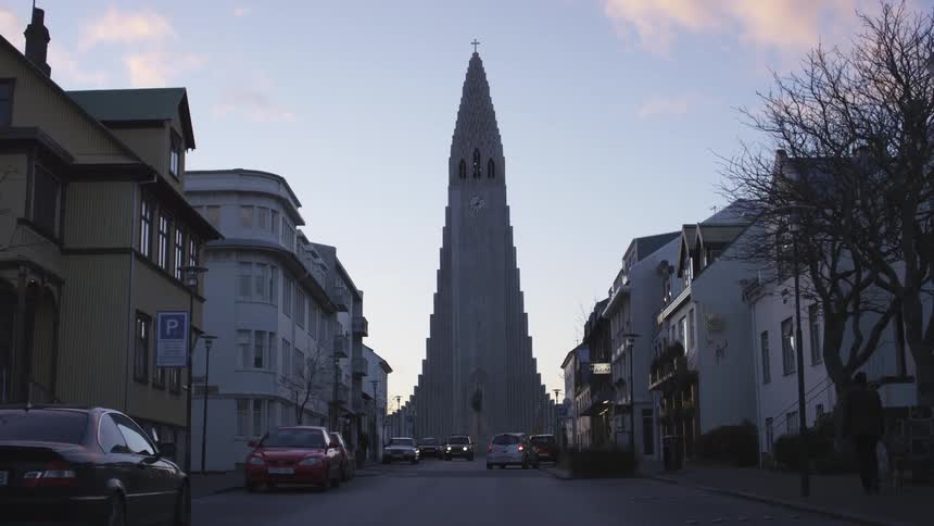 A tall church at the end of a street at dusk
