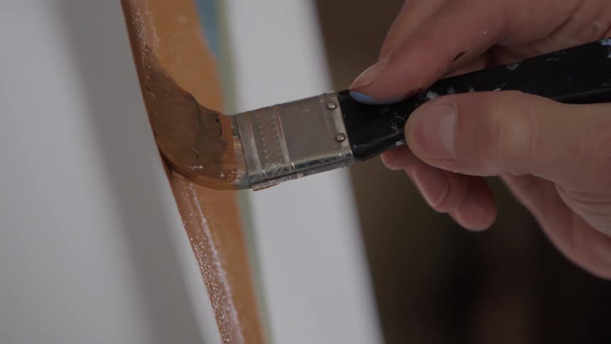 A person paints with a small paintbrush