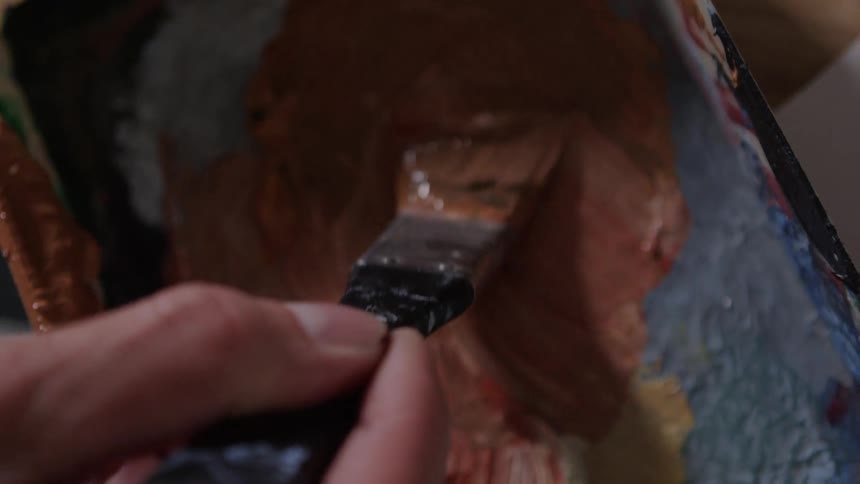 A person paints with a small paintbrush