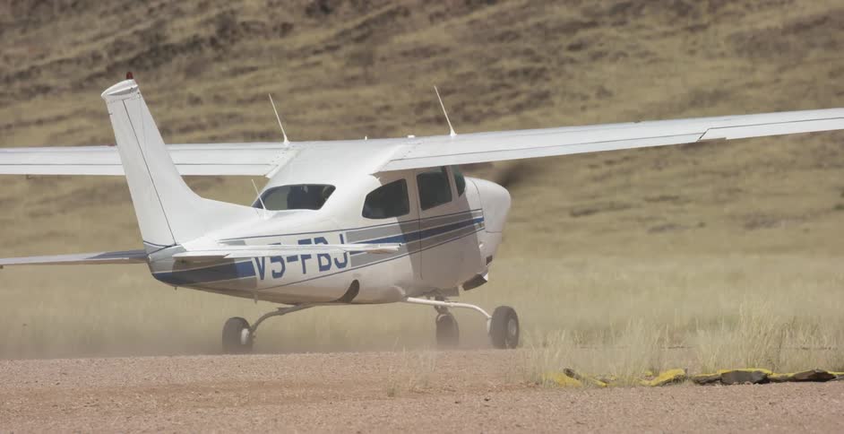 A small airplane drives on a dirt road