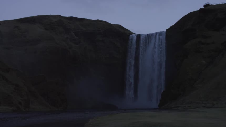 A waterfall flows down a precipice into a river