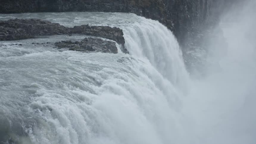 A waterfall gushes over a cliff