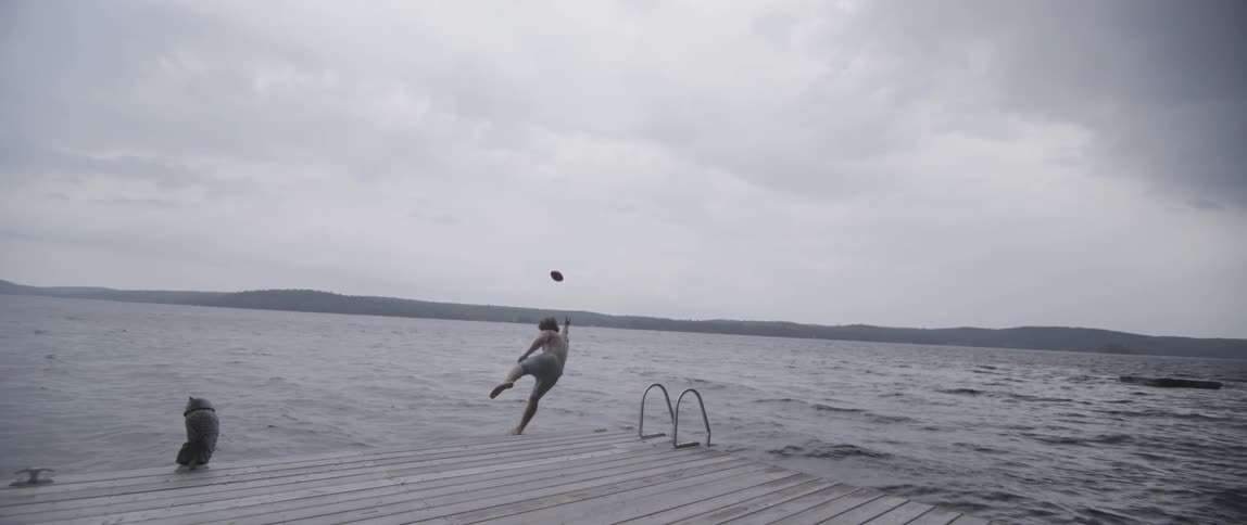 A man jumps into the lake while trying to catch the ball