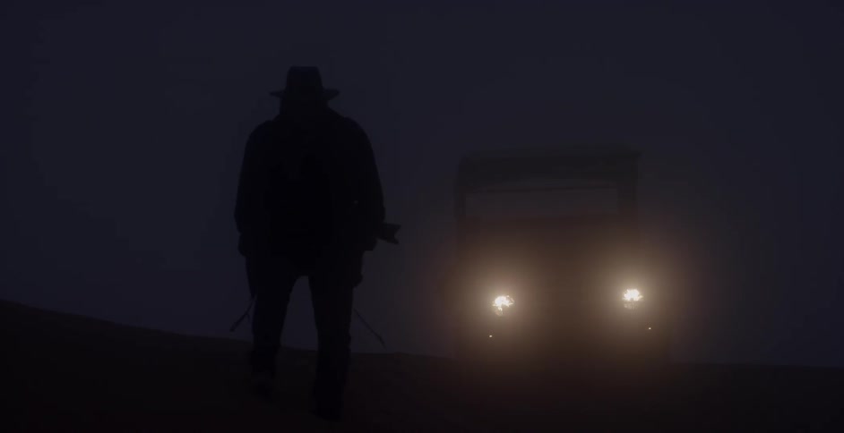 A man walks on the side of a road at night