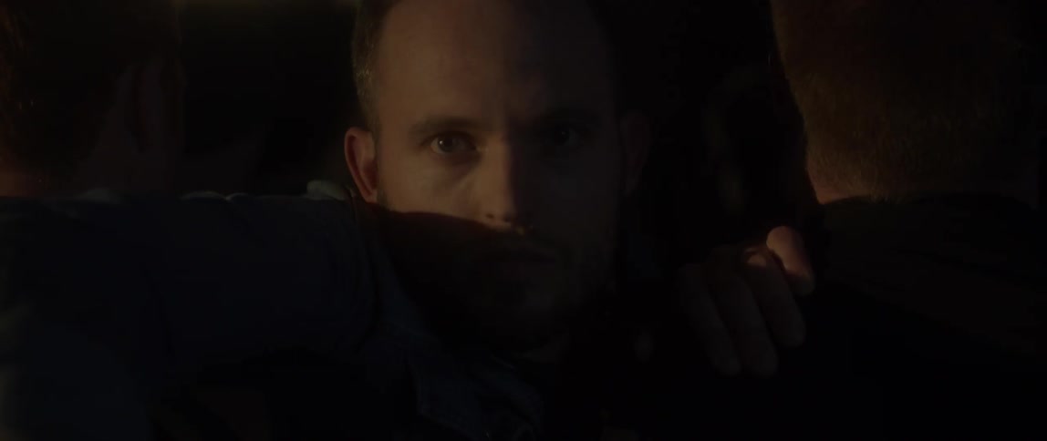 A guy is holding on to peoples shoulders at a room with flashing lights