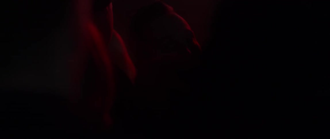 A man pushes his way through a crowd as lights flash