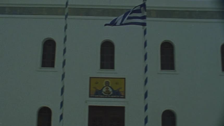 A flag is flying in the wind in front of this building
