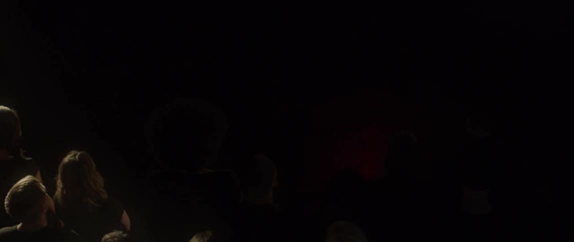 A group of people stand still as lights strobe around the room
