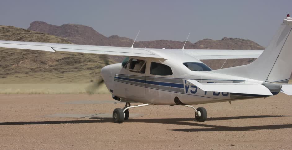 A small airplane drives on a dirt field